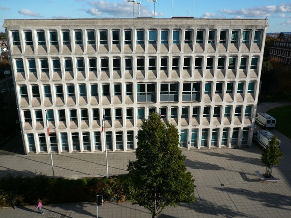 Aerial view of a square building with a tree in front