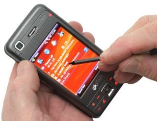 Hands holding E-TEN Glofiish M800 smartphone with stylus.