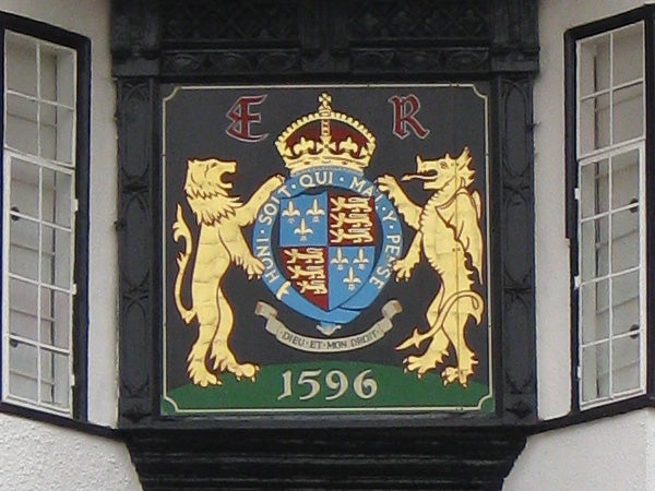 Coat of arms with lions and a crown, displayed on building.Coat of arms on building facade with date 1596.