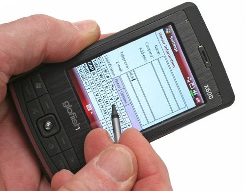 Hand holding an E-TEN Glofiish X600 smartphone with keyboard.