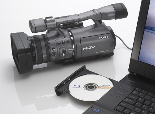 Sony HDR-FX7E camcorder beside a laptop and miniDV disc.Sony HDR-FX7E camcorder with laptop and miniDV tape.