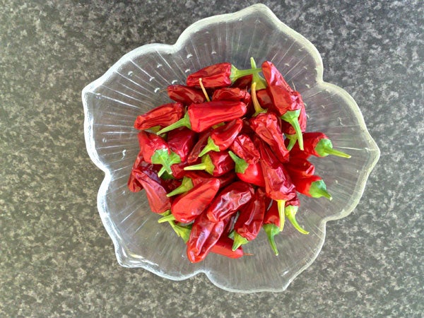 Bowl of red chili peppers on a kitchen counter.Bowl of wilted red chili peppers on a countertop.