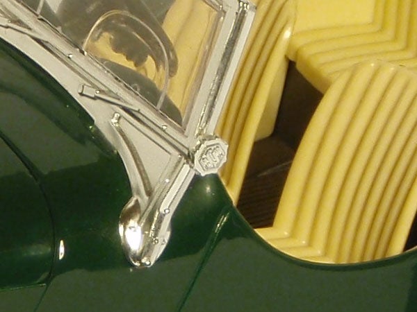 Close-up of a toy car's silver windshield frame and green hood.Close-up of a green model car with clear details