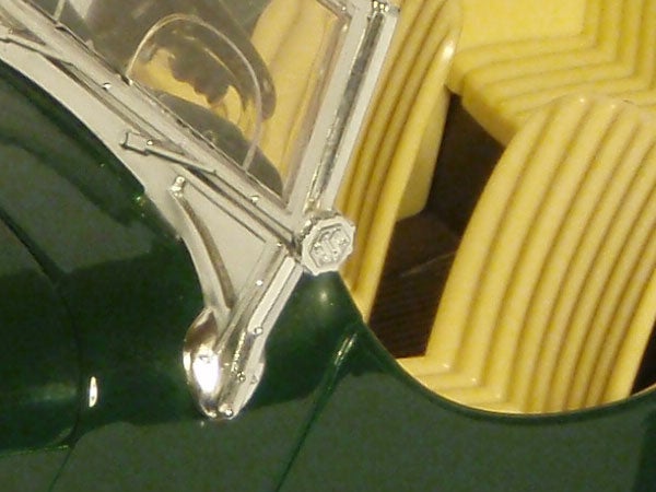 Close-up of a green toy car and yellow plastic object.Close-up of a green Olympus mju 790 SW camera.