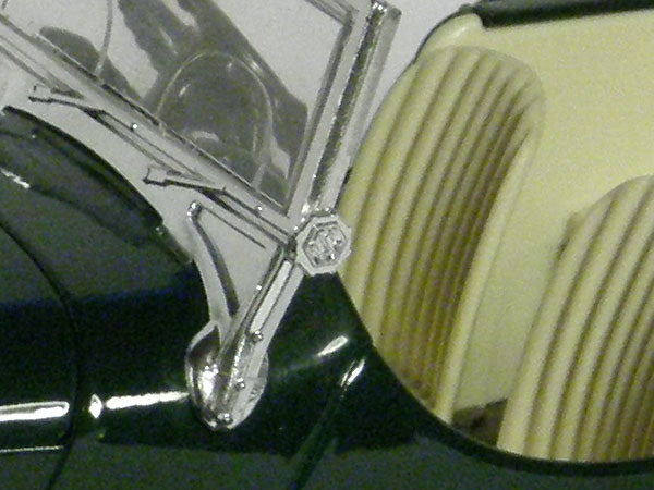 Close-up of Olympus SP-560UZ camera's zoom detail.Close-up photo of a vintage car hood and emblem