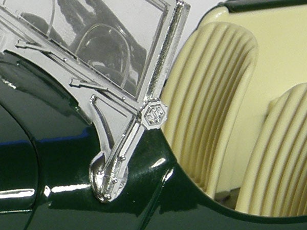 Close-up of Olympus SP-560UZ's zoom lens and chassis detail.Close-up of a vintage car hood and ornament.