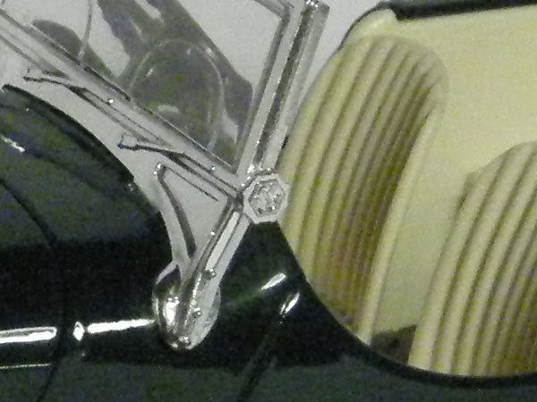Close-up of a classic car's chrome emblem and headlight.Close-up of a camera's lens taken by Olympus SP-560UZ.