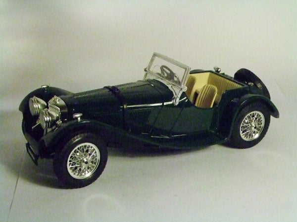 Model of a classic green sports car with detailed interior.Model of a vintage green sports car with white tire spokes.