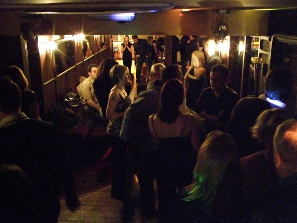 Low-light photo of people socializing in a dimly lit room.Low-light photo of people at a party using Fujifilm FinePix F50fd.