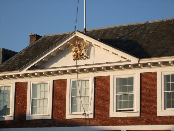 Golden coat of arms on a red-brick building facade.Photo of a building facade with decorative crest taken in sunlight