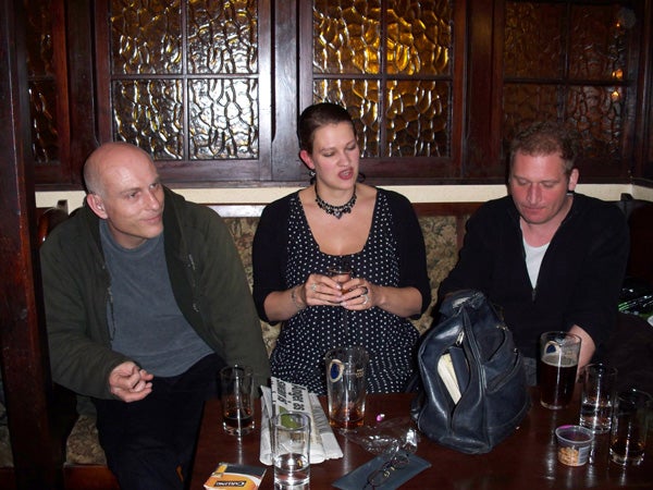 Three people sitting at a pub table with drinks.Three people socializing at a pub table with drinks.