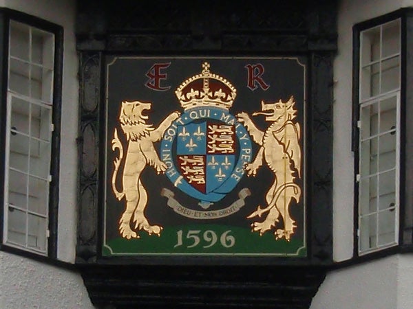 Ornate heraldic crest with lions and a motto on a building.Coat of arms on a building facade with date 1596.