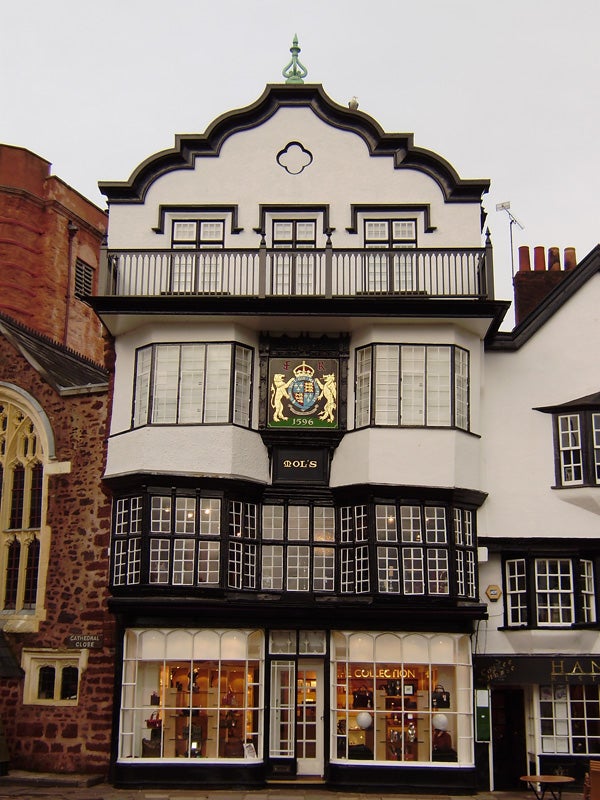 Historic half-timbered building with decorative crest and shopfront.Historic half-timbered building with a dated crest.