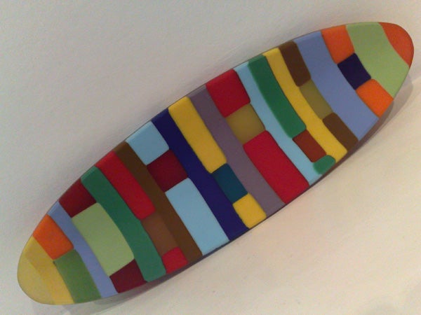 Colorful abstract art on an elliptical canvas.Colorful surfboard-shaped object with a patterned design.