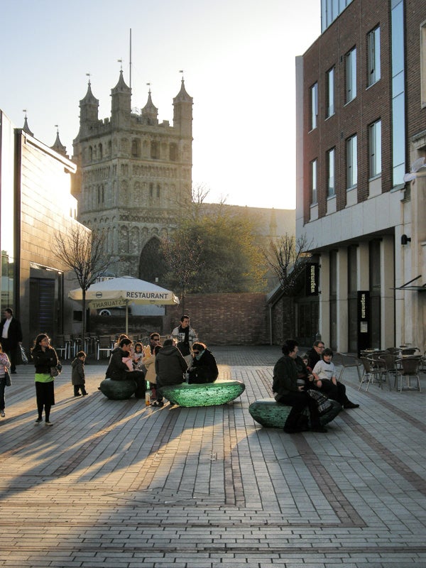 People relaxing in urban plaza in evening light.