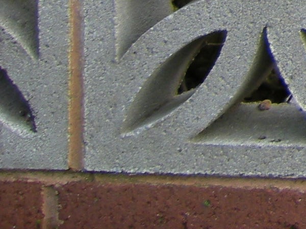 Close-up photo of decorative metalwork with brick background.