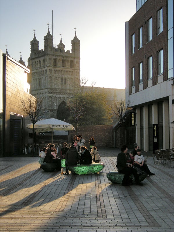 Outdoor photo of people near historic building at sunset.