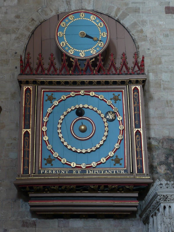 Intricately designed antique astronomical clock on a wall.