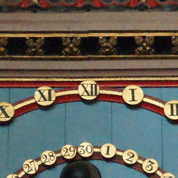 Clock face with roman numerals and circular calendar dates.