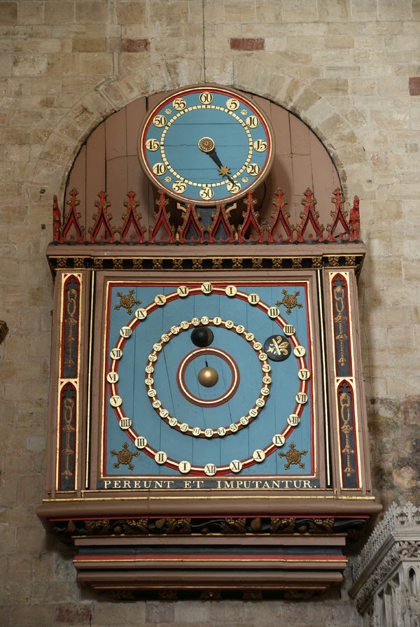 Ornate astronomical clock on an ancient stone wall.