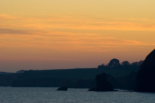 Silhouetted coastline during sunset captured with Sony Alpha A200.