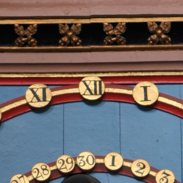 Close-up of a clock face with Roman numerals and dates.