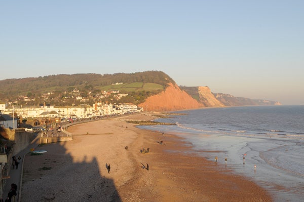 Seaside landscape at sunset with long shadows and cliffs.