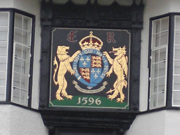 Coat of arms with lions and a crown on building facade.