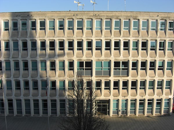 Bare concrete building facade with numerous square windows and shadow.Photo of a building facade with rectangular windows taken at a distance.