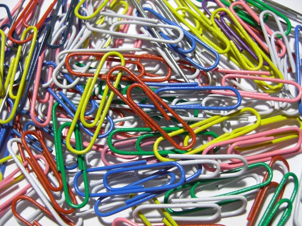 Colorful paperclips scattered on a white background.Close-up of colorful paperclips on a white surface.