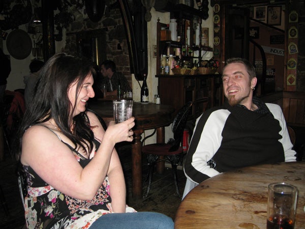 Two people laughing in a pub setting.Two people smiling and socializing in a pub.