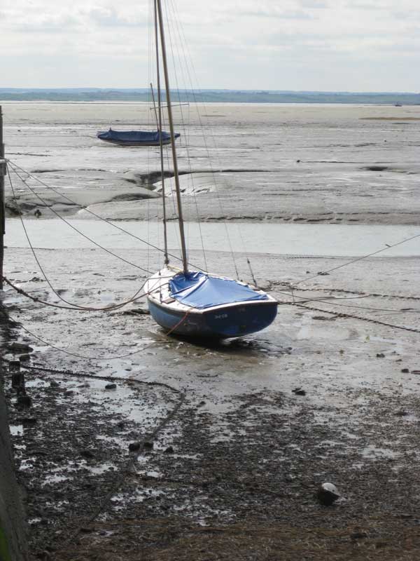 Sailboats on a mudflat at low tide.Sailboats grounded at low tide with cloudy sky.