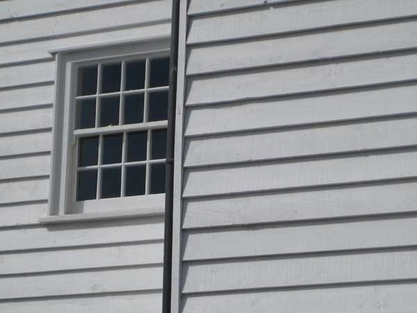 Photo of a white wooden building with window and drainpipe.White house siding with window, taken by Canon IXUS 80 IS.