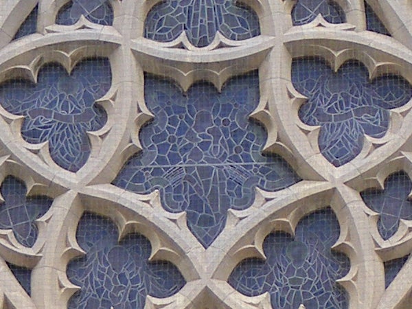 Detailed stonework of gothic architecture with blue tint.Intricate stone lattice work on a building facade.