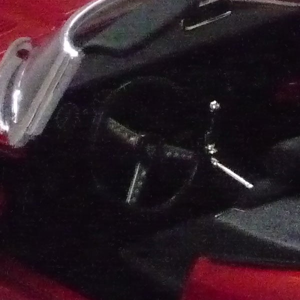 image of an object on a red surface.Low-light photo of a watch captured with Panasonic Lumix DMC-TZ4.