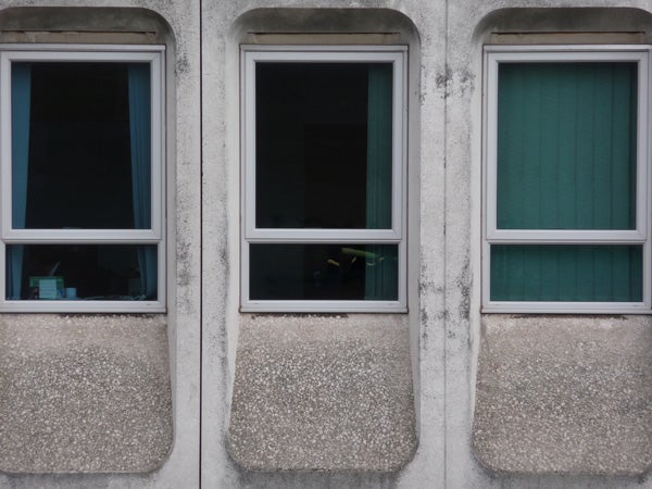 Three windows on a textured concrete building facadeThree rectangular windows on a concrete building facade