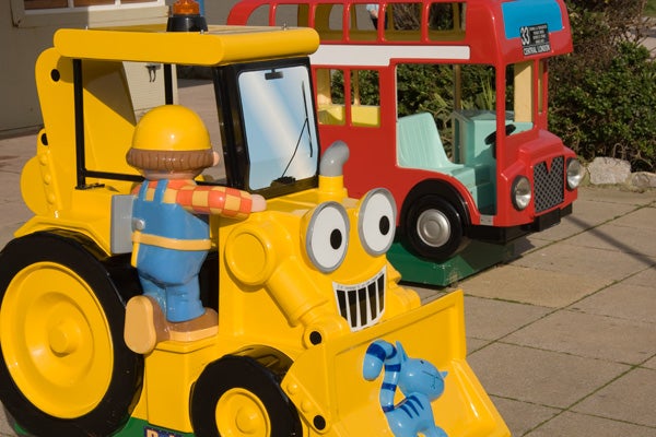 Colorful toy excavator and bus on pavementColorful children's play equipment resembling vehicles with cartoon faces