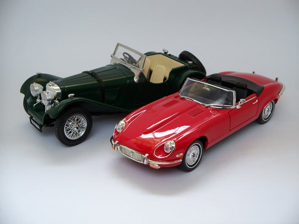 Two die-cast model cars, one green and one red, displayed together.Two model cars, a green classic and a red convertible.