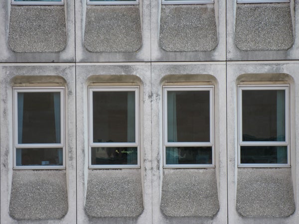 Six windows on a textured building facade.Concrete building facade with six rectangular windows.
