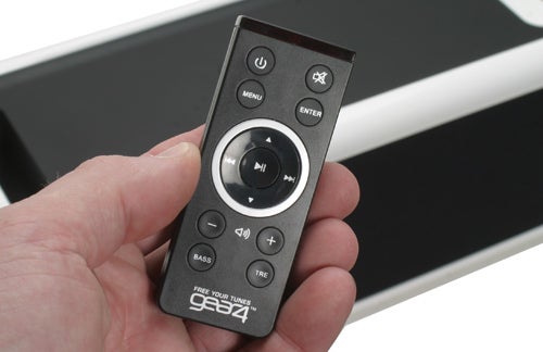 Hand holding Gear4 BassStation remote control.Hand holding Gear4 BassStation remote control with buttons visible.