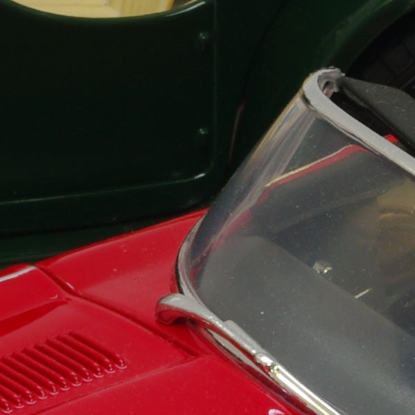 Close-up of a red model car's hood and windshieldClose-up photo of a red toy car and part of a green toy car.