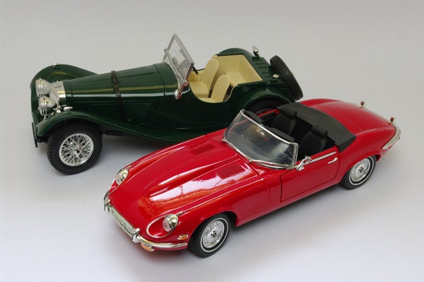 Photo of two model cars, one red and one greenRed and green toy convertible cars on white background