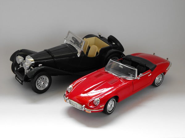 Two model cars on a gray background.Model cars on display, black vintage and red sports car.