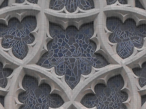 Patterned stone facade with blue mosaic details.Intricate gothic window patterns with cracked glass effect