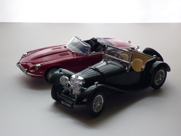 Two vintage model cars on a white background.Vintage and modern model cars on display