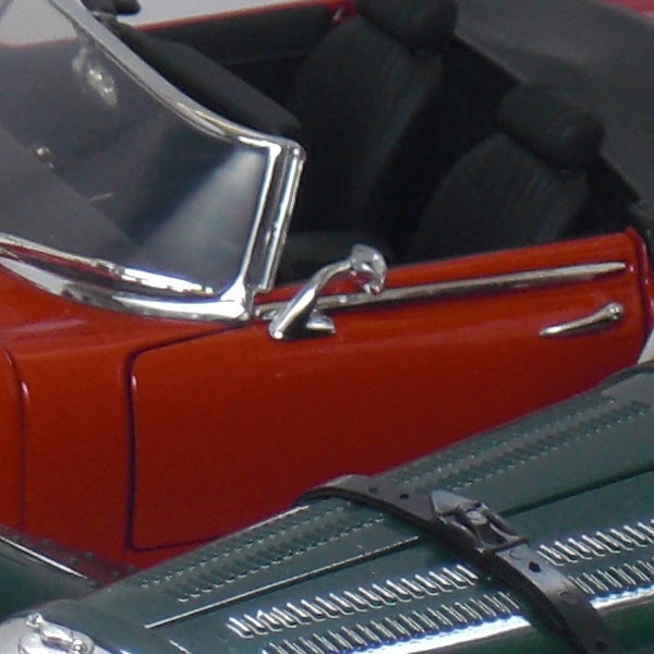 Close-up of a red and green model car cabin and hood.Close-up of a red and green toy car