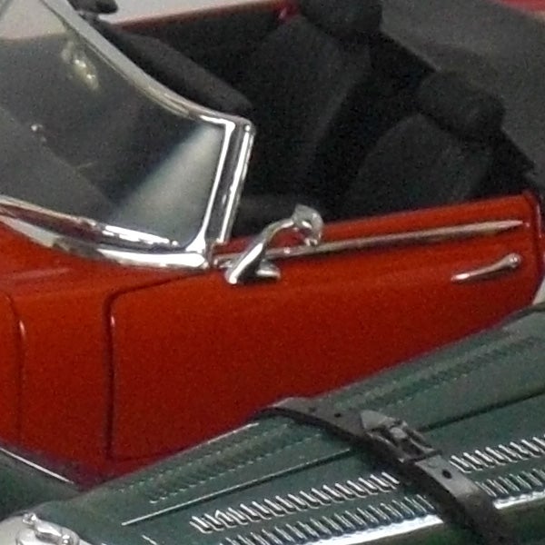 Close-up of a die-cast model car door and handle.Close-up of a red vintage car door and side mirror.