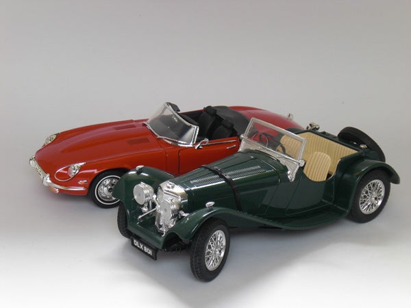 Two vintage model cars on a white background.Model cars on display, including a green and a red car.