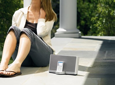 Woman sitting next to a Bose SoundDock Portable speaker.Woman sitting next to a Bose SoundDock Portable outdoors.