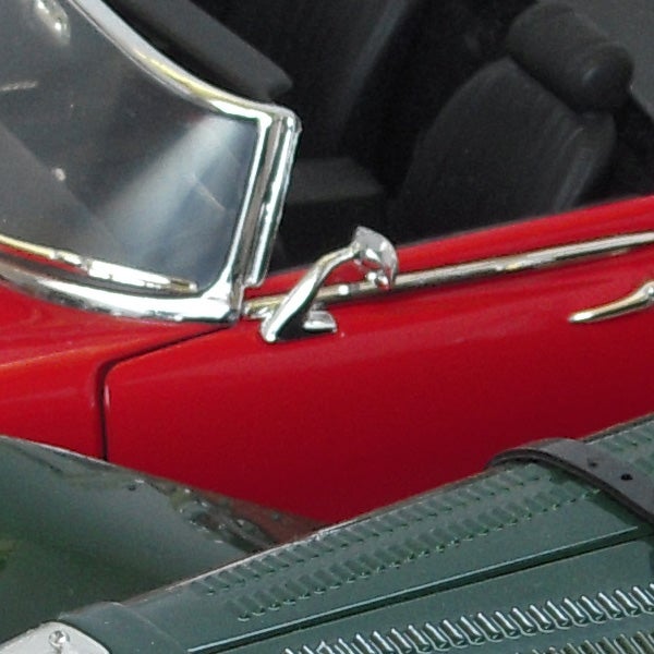 Close-up of a red vintage car with a chrome detail.Close-up of a classic red car's front detail.